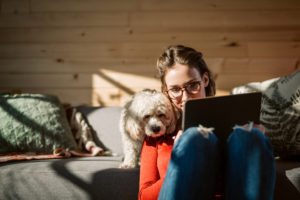Woman on laptop with her dog using Norton Secure VPN